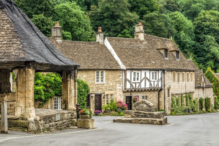 an old stone building with Cotswolds in the background