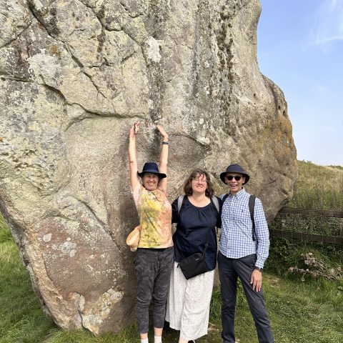 a group of people standing in front of a rock