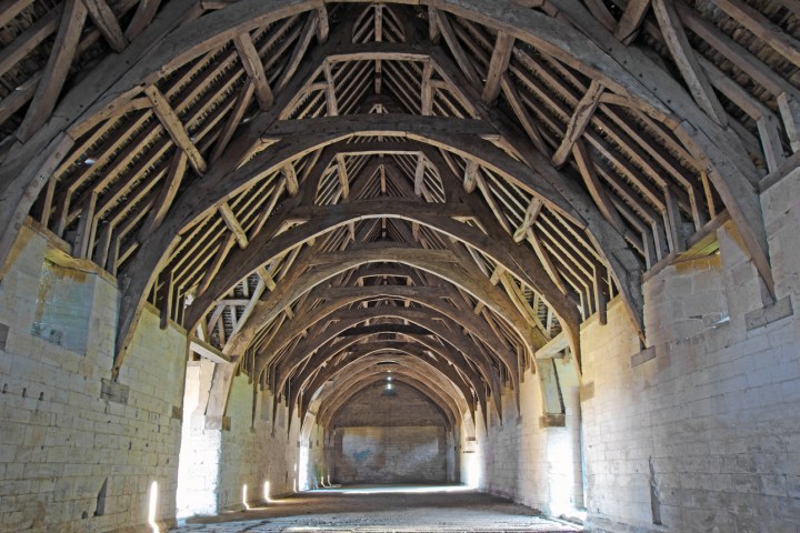 Interior of a medieval stone hall with timber roof beams and arched ceiling.