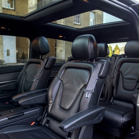 Interior of a luxury vehicle with black leather seats and open side door.