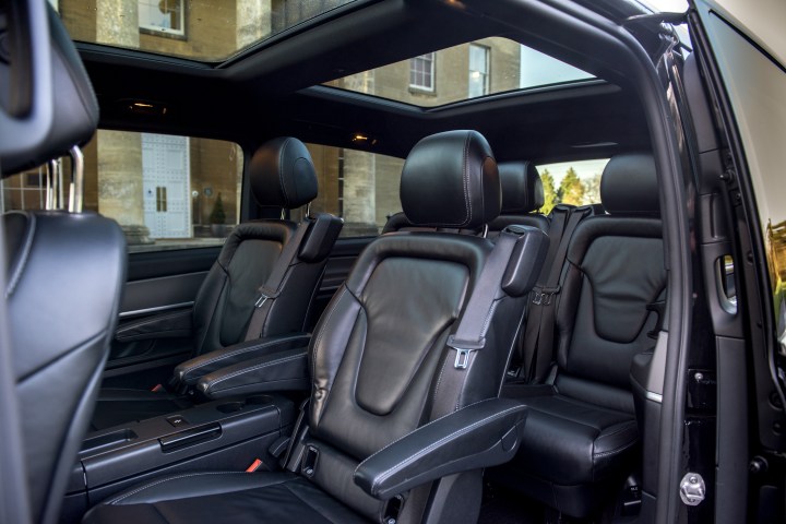 Interior of a luxury vehicle with black leather seats and open side door.