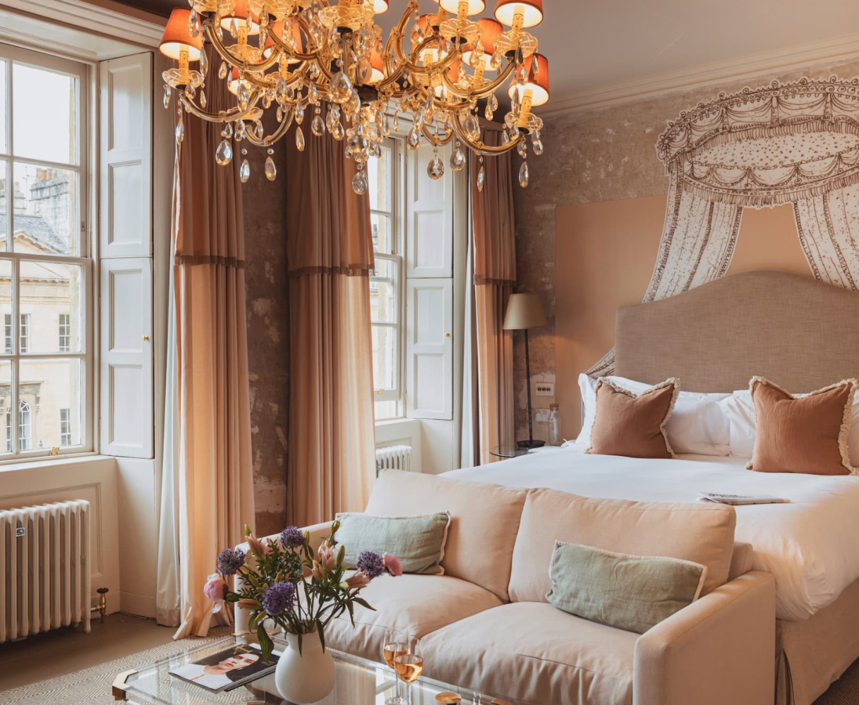 Elegant bedroom with chandelier, large bed, and plush sofa.