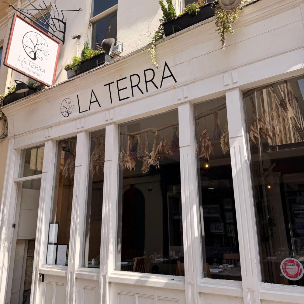 Exterior of 'La Terra' restaurant with plants and dried flowers.